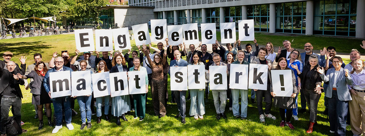 Mitarbeiter halten Papierbuchstaben in die Höhe, auf denen Engagement macht stark steht.